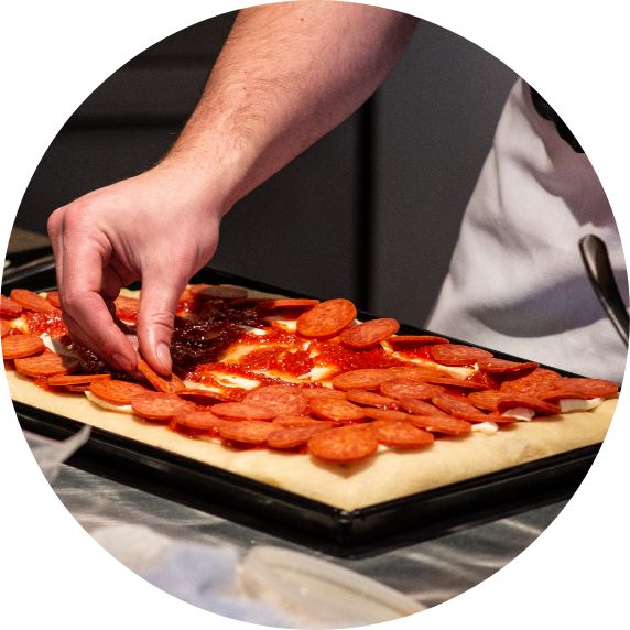 laying out pepperoni on dough to be cooked