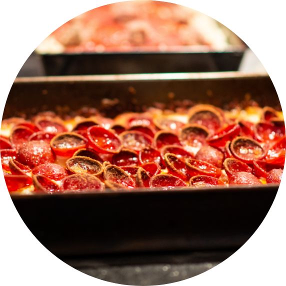 side-shot of pizza in a pan with cupped and charred pepperoni